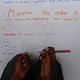 Kinderhände schreiben Regeln auf ein Plakat