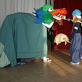 Kind und Drache mit Pappkopf auf einer Bühne